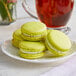 A white plate with three Coco Bakery pistachio macarons.