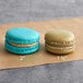 Two Coco Bakery salted caramel macarons on brown paper, one blue and one brown.