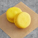 Two yellow Coco Bakery Meyer Lemon Macarons on brown paper.