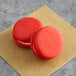 Two red Coco Bakery red velvet macarons on brown paper.