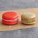 Two Coco Bakery red velvet macarons with white filling on brown paper.