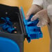 A person in white gloves holding a Vikan blue plastic cleaning station.