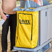 A man holding a yellow Lavex vinyl bag on a cart.