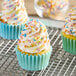 A frosted cupcake with India Tree Nature's Colors sprinkles on a cooling rack.