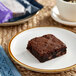 An individually wrapped Killer Brownie on a plate next to a cup of coffee.