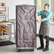 A man in an apron standing next to a large grey JackStack thermal cover.