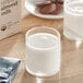 A glass of Mooala Organic almond milk next to a cookie.