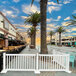 A white Mod-Traditional fence with white posts on a sidewalk.