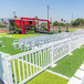 A white Mod-Traditional fence with chairs on grass.