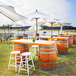 A white Mod-Picket umbrella on a wooden table with white chairs and a barrel with silver bands.