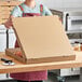 A woman holding a Choice kraft cardboard pizza box.