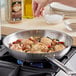 A person seasoning a pan of food with McCormick Grill Mates Cracked Black Pepper and Garlic with Sea Salt.