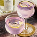 Two glasses of pink Optimist Botanicals with lemon slices and lavender on top.