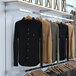 A white metal wall rack with shelves holding shirts and jackets.