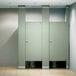 A row of ASI stainless steel bathroom stall partitions with two doors and two toilets.