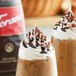 Two iced coffee drinks topped with whipped cream and dark chocolate sauce on the rim.