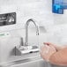 A person washing hands under a Waterloo wall-mount hands-free sensor faucet.