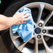 A person cleaning a wheel with a blue Monarch Brands huck towel.