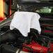 A white Monarch Brands shop towel on a car engine.