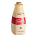 A close up of a Torani Puremade White Chocolate Flavoring Sauce bottle with a red label.