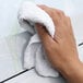A hand holding a white Monarch Brands bar mop terry towel.