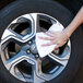 A hand using a white Monarch Brands utility terry towel to clean a wheel.