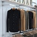 A wall-mounted retail display rack with shirts and jackets on hangrails.