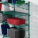 A Regency green metal wall-mounted wire shelf with containers and dishes on it.