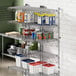 A Regency stainless steel wire shelf post with single brackets holding white and blue plastic bins.