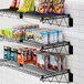 A black Regency wall-mount wire shelf with food and snacks on it.