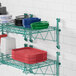 A Regency green wire wall shelf with dishes and plates on it.