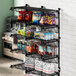 A Regency black metal wall-mount shelf with snacks and drinks on it.