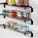 A Regency black wire shelf with food and snacks on it.
