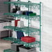 A green metal Regency wall-mount shelf with dishes and containers on it.