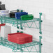 A green metal Regency wall-mount shelf with dishes and plates on it.