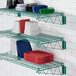 A green metal Regency wall-mount wire shelf with red and blue plastic plates on it.