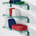 A green Regency wall-mount wire shelf with plastic plates and bowls on it.