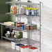 A Regency chrome wall-mount shelf post with single brackets holding shelves with food cans on it.