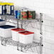 A Regency stainless steel wall-mounted wire shelf with food containers and cans on it.