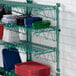 A green Regency wall-mount wire shelf with plastic plates on it.