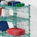 A Regency green metal wall-mount shelf with red plastic plates on it.