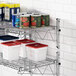 A Regency chrome wire shelf post with a white shelf holding white and red food containers and cans.