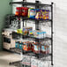 A Regency black metal wall-mount shelf with food and snacks on it.