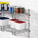 A Regency chrome wall-mount wire shelf with food containers and cans on it.
