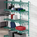 A green metal Regency wall-mount shelf with containers on it.