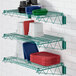 A green Regency wall-mount wire shelf with dishes and plates on it.