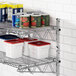 A metal Regency wall-mount shelf with white containers and cans on it.