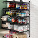 A Regency black wire wall-mount shelf unit with food and snacks on it.