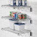 A Regency stainless steel wire shelf with a white and blue container and canned food on it.