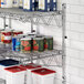 A metal Regency wire shelf with canned food on it, including a can of tomato sauce and white and blue containers.
